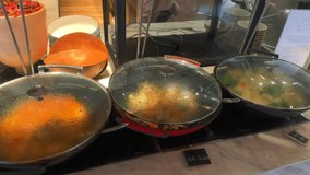 Food at a buffet breakfast. Cooking pans with food. Fry pans with lids. Restaurant buffet breakfast. Food at a restaurant.
