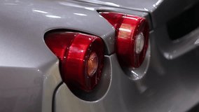 rear lights of a sports car. Large red round tail lights of a racing modern sports car. round red tail lights of a modern sports car. round tail lights of a gray sports car. horizontal video