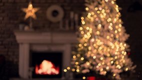 Christmas tree in cosy decorated living room at home with fireplace. December winter mood. Blurred out of focus background video for holiday ads and offer.