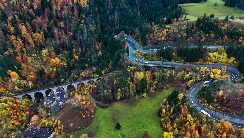 Aerial drone view winding mountain road between autumn trees. Vehicles driving through the curve. Serpentine road in southern Germany. High quality 4k footage Royalty-Free Stock Footage #1111142187