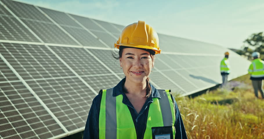 Face of woman at solar panel farm for clean energy, outdoor electricity maintenance and smile. Sustainability, photovoltaic power system and happy technician with helmet for safety inspection.