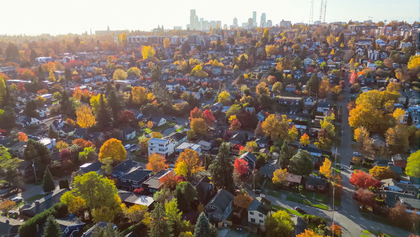 Flying high above a Seattle suburban neighborhood at sunset with a view of downtown in the distance