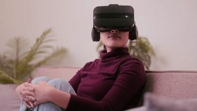 Asian young woman is enjoying virtual reality (VR) on the sofa in the cozy living room during the Christmas night. Immerse in the festive spirit with VR experiences