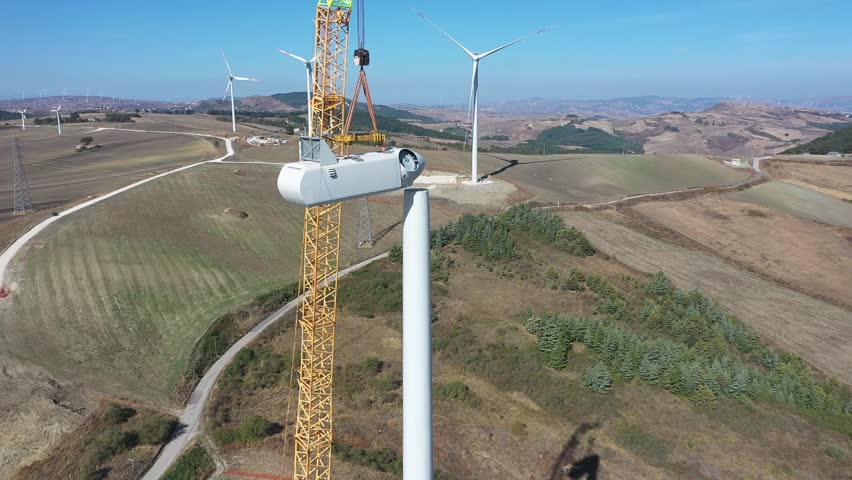 Aerial view of wind turbine under construction.
Wind turbines are part of the energy transition strategy.
Drone view in a sunny day in farm landscape. Sustainable growth.