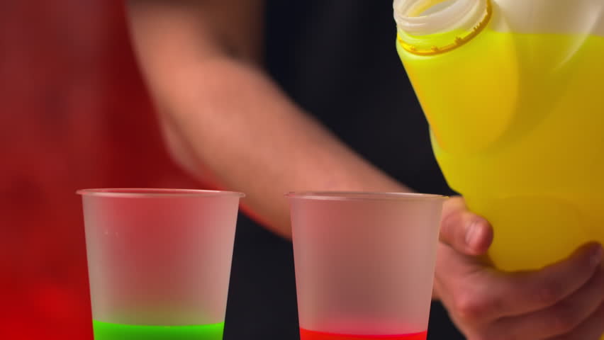 Worker mixes colors by pouring paint into cups with other paint. Man pours paint from bottle into cup creating new color for movie decoration