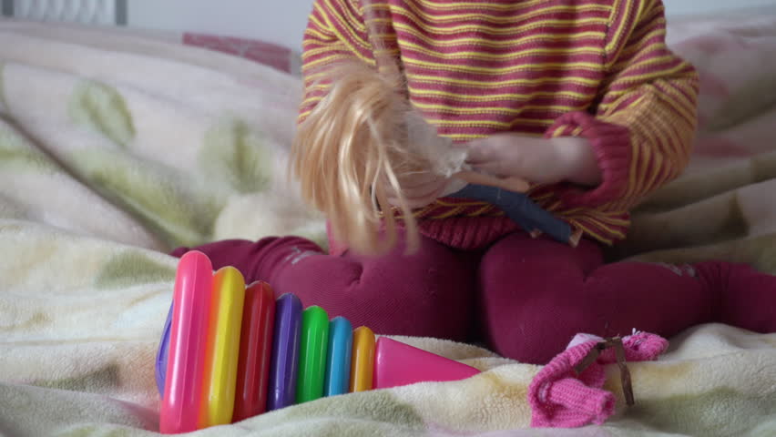 a girl is playing with a doll on the bed,the child
