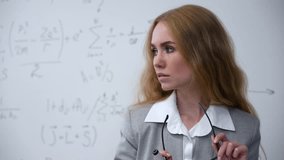 Caucasian female teacher stands at a white board with written formulas.  - Powered by Shutterstock - Get 15% off with code: PIKWIZARD15