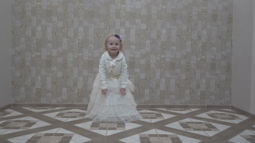 a little girl is circling in a white dress in the room,cheerful girl in a dress like a princess dances in an empty room