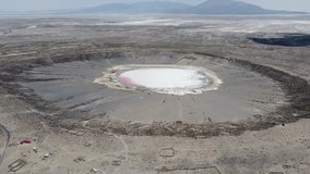 Camera moving over the Chipaya Meteor impact crater Bolivia with white and pink water in the crater Aerial video