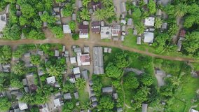African village aerial drone top shot clip. Wooden houses on a dusty road in the forest.