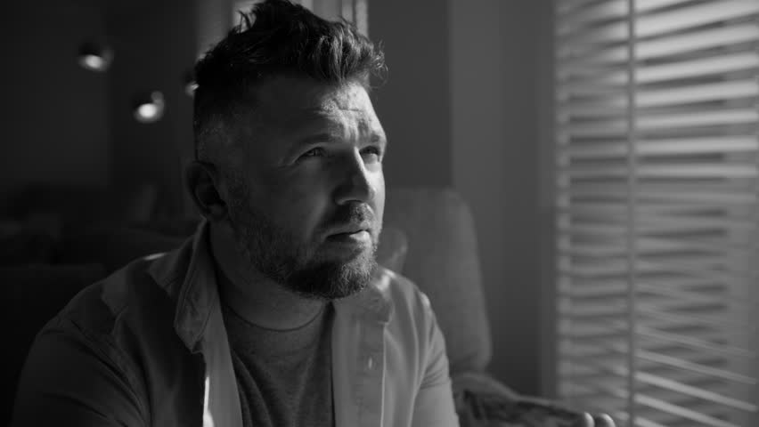 Black and white shot Handsome male sits alone at home troubled negative thoughts slowmo. Pensive deep in sad thoughts man looking window. Sad thoughtful mature 40s man portrait thinking of problems Royalty-Free Stock Footage #1111171705