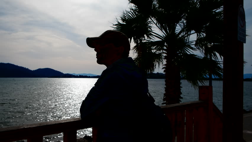 Silhouette of a woman looking at the sea on the bridge. Woman tourist enjoys the seascape.