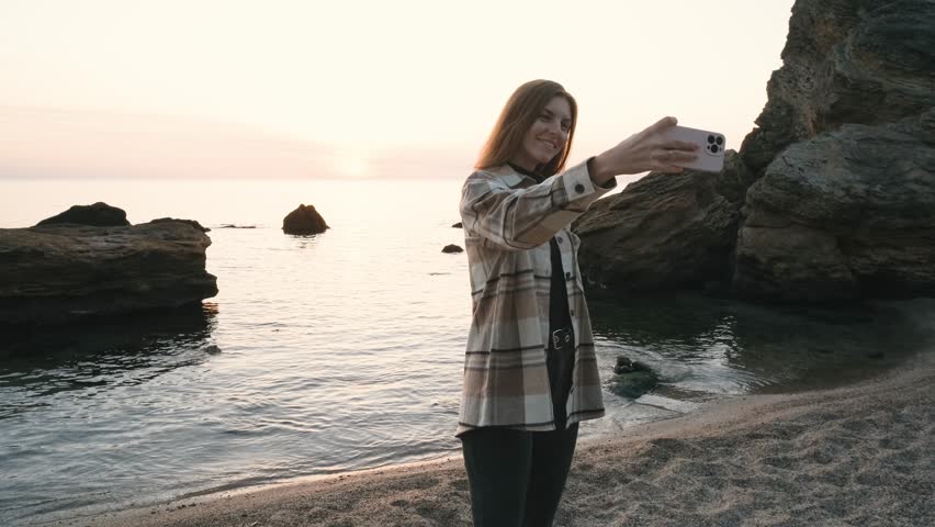 Happy beautiful red-haired woman make picture on smartphone at beach, laughing and smiling to camera