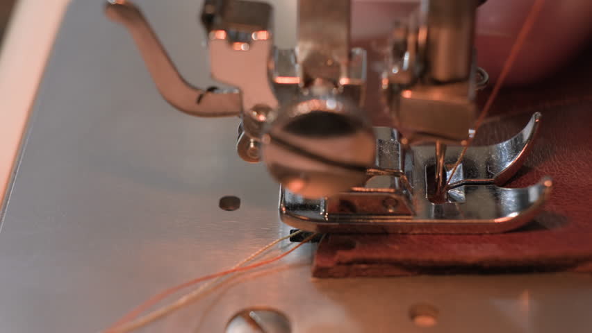 Leatherworker tailor sews leather product on sewing machine close-up.
