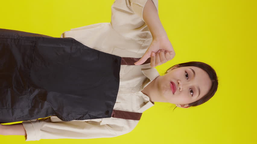 Portrait of young asian barista woman wearing apron standing and unhappy gesture dislike on yellow background, waitress or entrepreneur disappointed, small business or startup with failure. | Shutterstock HD Video #1111181049