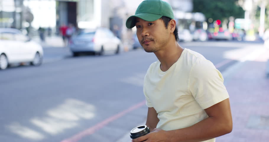 Person, coffee and phone for talking in city, outside or street for communication with drink. Asian man, student and cap for walking in New York with mobile for connectivity, cellular or internet