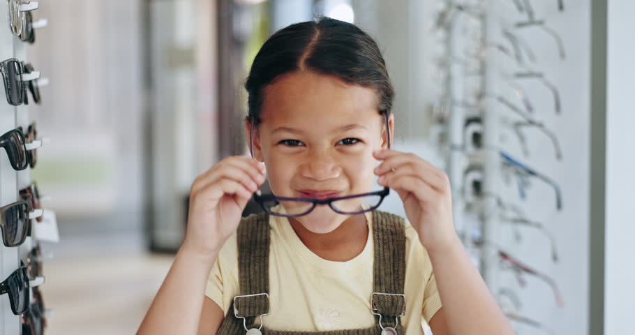 Happy girl, kid and glasses for eyewear by shopping in optometrist office for corrective, lens and frame. Young person, excited and emoji with smile for choice with spectacles, eye care and health Royalty-Free Stock Footage #1111183705