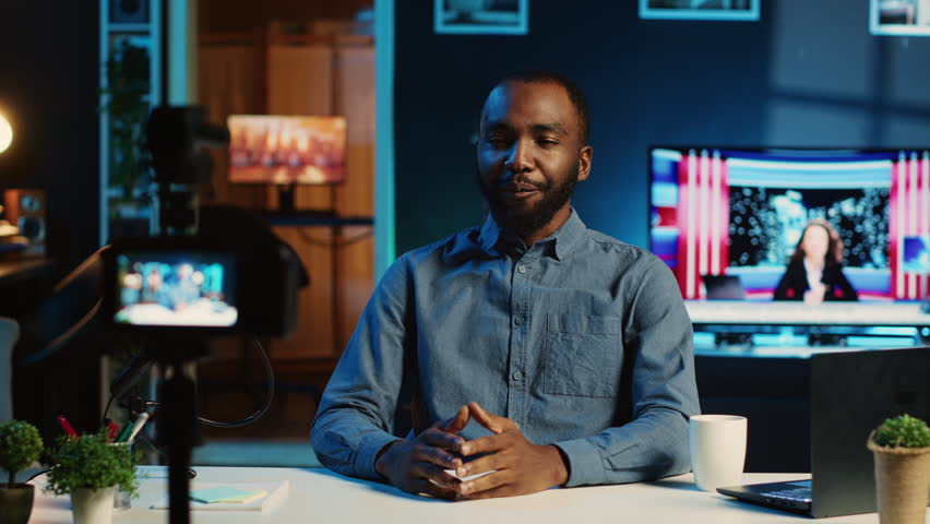 Cheerful content creator using professional recording camera in cozy studio to film video intro for online streaming platforms. Influencer greets fanbase, talking from personal living room