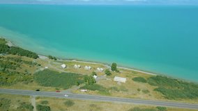 Aerial view of houses and boats, trees, beach big blue azure lake sea in clear sunny weather. Drone video, flying in an arc. Lake Sevan, Armenia.
