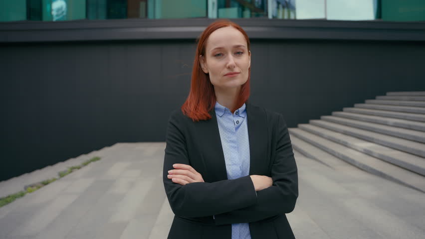 Portrait strong pose confident serious Caucasian red ginger haired business woman posing in city outdoors in middle of modern urban office building hands crossed confidence businesswoman crossing arms Royalty-Free Stock Footage #1111188579