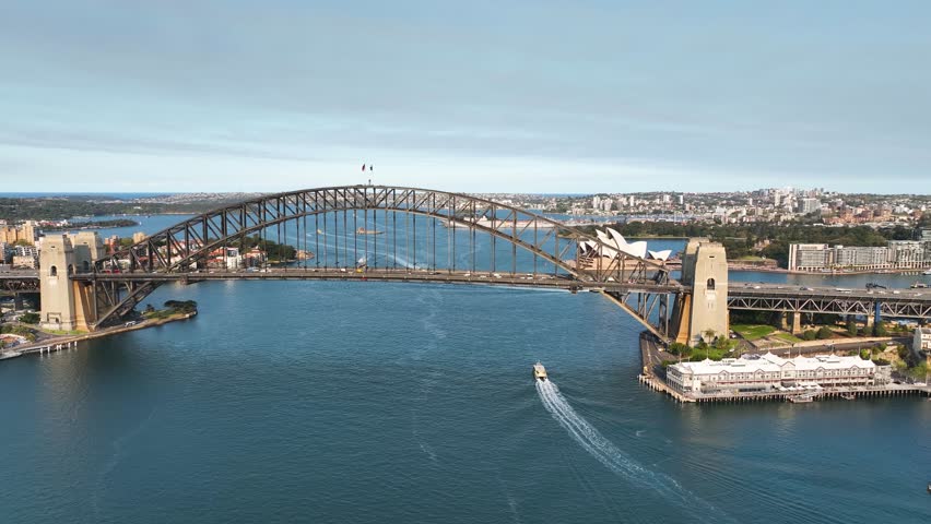 Views of Australia. Aerial View Of Sydney Harbour Bridge Lifting Up To Reveal Sydney Opera House Behind At Sunset.