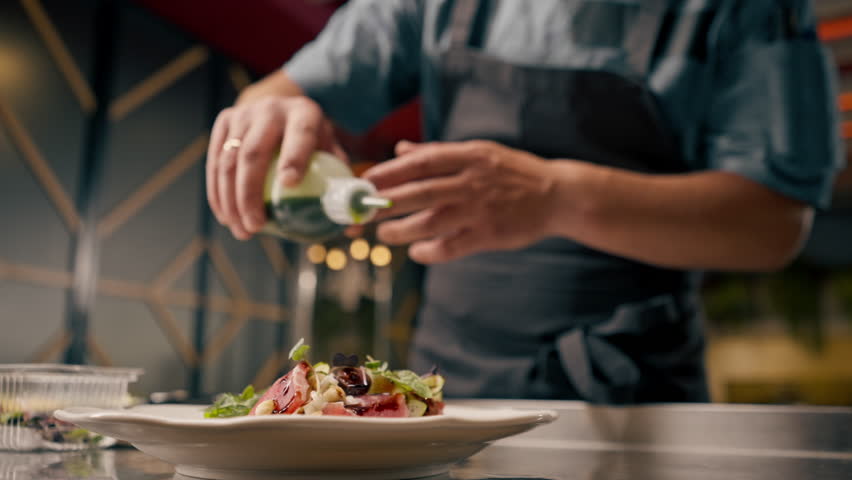 close-up Chef holding a bottle of sauce and topping bruschetta with it in the kitchen of Italian restaurant Royalty-Free Stock Footage #1111190893