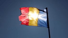 Romanian flag. 4K video with the flag of Romania waving in the wing against sunny blue sky landscape. Concept image for Romania.