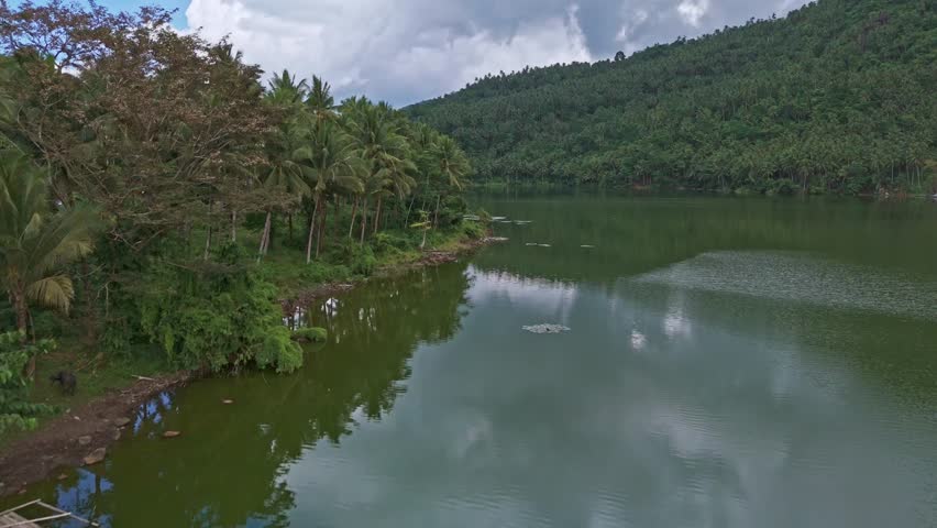 An aerial drone shot over Mahucdam Lake, with tropical jungle covered hills surrounding the water. Surigao Del Norte, Philippines. 