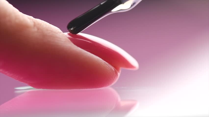 Applying Nail polish, pink shellac UV gel, varnish, manicure process concept in beauty salon. Transparent top coat drop on brush. Over pink background. Application of nail polish. Slow motion Royalty-Free Stock Footage #1111193843