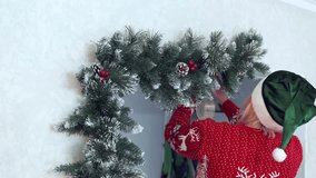 Young woman in an Elf costume decorates her house for Christmas using festive garlands of artificial fir branches, cones and berries. Holiday spirit. Christmas eve. - Powered by Shutterstock - Get 15% off with code: PIKWIZARD15