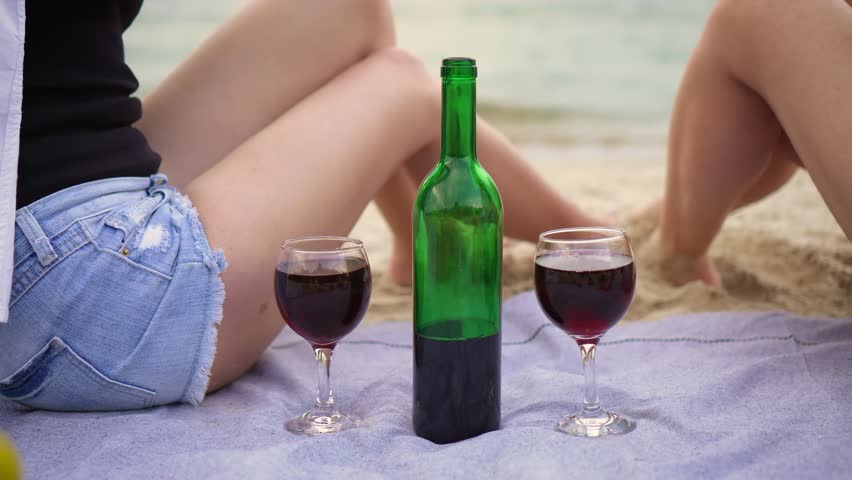 Close up Lesbian women couple in joyous celebration of their vacation, drinking wine by sea beach. Beautiful romantic moment between two lesbian lovers