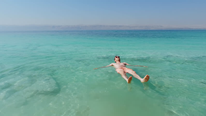 Young Caucasian Man Floating in the Dead Sea. Lowest Elevation on Earth. Jordan Rift Valley