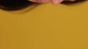 Young lady enjoying while biting macaron, isolated on yellow background, copy space, close up. Sweets food concept. Real time vertical video