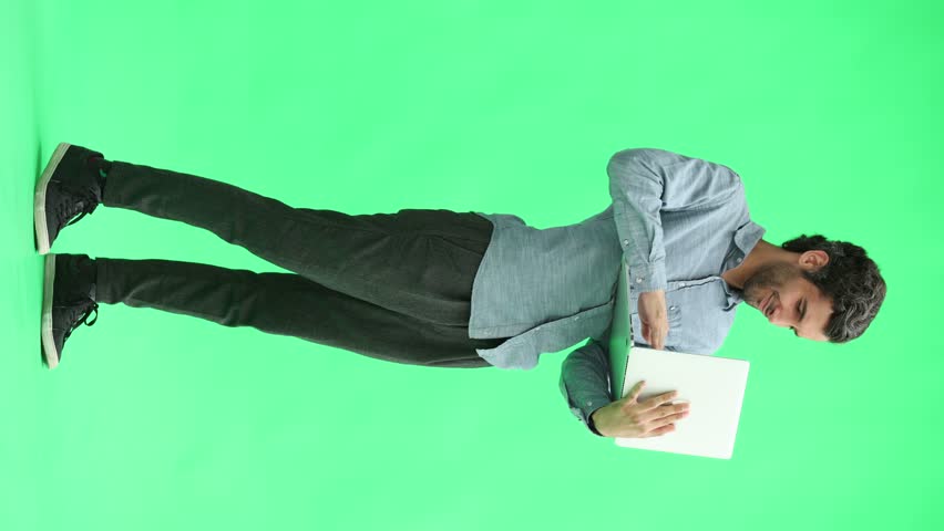 young man in full growth. isolated on green background using laptop