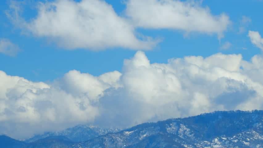 White Clouds Opposite Direction Glide Between Mountain Peaks. Iconic View Of Winter Wonderland Winter Background. Timelapse.