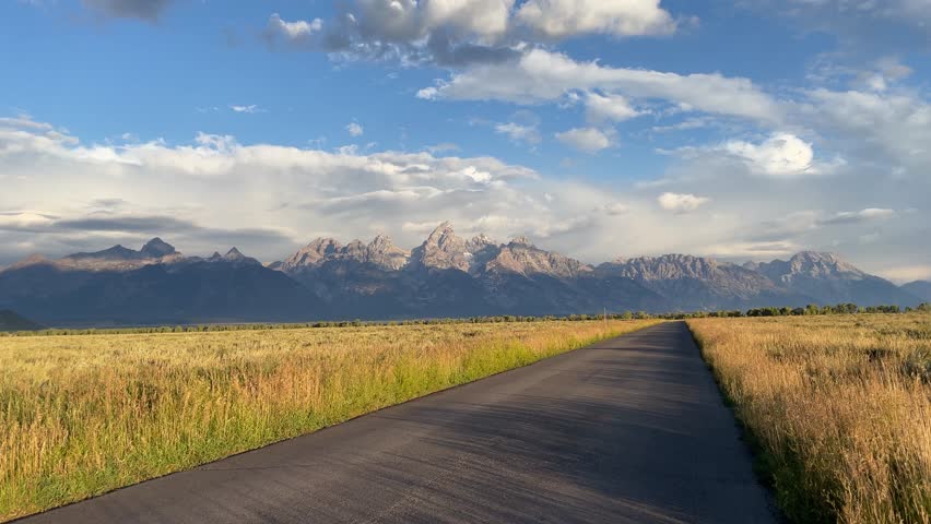 Road passes through Grand Teton National Park mountain range, Wyoming, USA