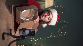 Technology Product Review. Female blogger unpacking a package with new wireless headphones recording a video for her technology blog at home. Christmas concept