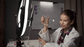 Schoolgirl blogger recording a video for her subscribers on social networks conducting simple chemical experiments