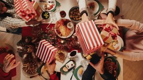 Friends giving presents to each other top view, celebrating new year, sitting at dining table. International young people making surprises. Diverse students during christmas party at home.  - Powered by Shutterstock - Get 15% off with code: PIKWIZARD15