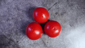 Ripe red tomatoes rotate on a darkbackground. View from above. Side light. 4k video.