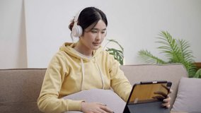 Young asian woman watching music video on digital tablet
