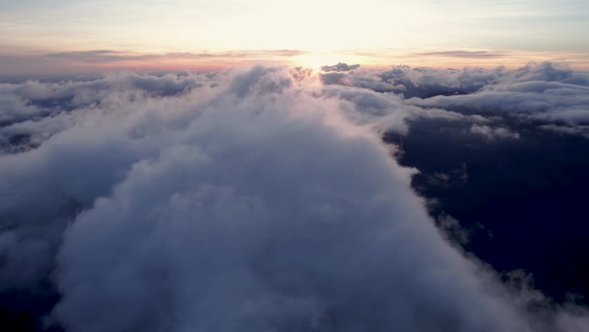 Aerial view of clouds covering mountain valley. Flying at sunrise