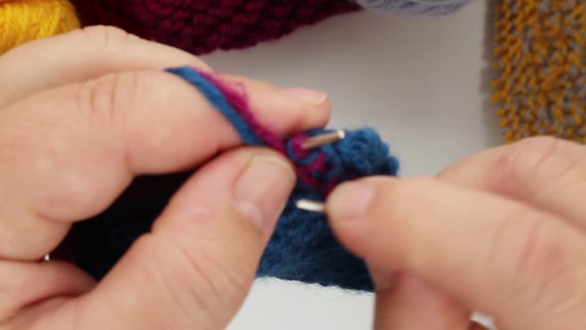 Women's hands are knitting with colored threads on a white background. Needlework, knitting, craft. Soothing, relaxing video. ASMR Royalty-Free Stock Footage #1111220583