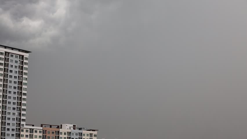 High-angle 4K video that sees condominiums of various sizes encircling the city center, business district, and blurry lights and passing cars during the evening twilight sky.