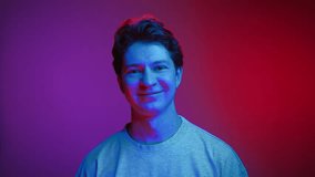 Happy Portrait of Young Man Looking at Camera and Smiling in Neon UV Colors of Filter. Shining Effect of Vivid Lighting and Backlight Illumination Inside Amazing Studio. Trendy Person with Cute Grin - Powered by Shutterstock - Get 15% off with code: PIKWIZARD15