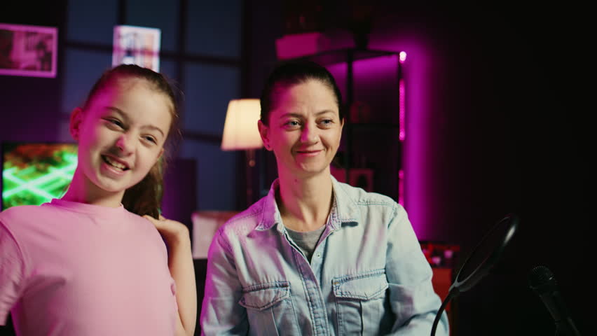 Daughter and mother filming reaction video for gen Z audience, preparing to look at online videos on laptop. Cute kid and her parent recording reaction to internet clips for family channel