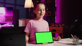 Cute child content creator filming technology review of newly released isolated screen tablet, unpacking it and presenting specifications to audience. Young online star showing mockup device to fans