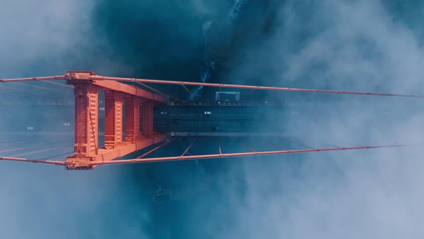Aerial of red Golden Gate bridge. Busy road of red bridge over deep blue Pacific Ocean waters. Top down fog drifting around industrial architecture construction in San Francisco bay, California USA 4K