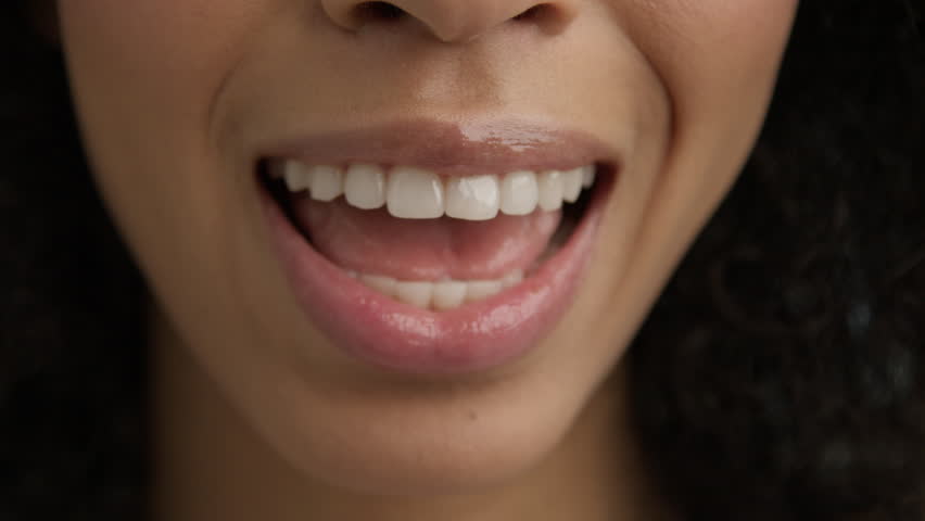 Macro background of mixed race female mouth speaking. Happy talking people close up. Expressive emotional fun and joy lifestyle concept. Young female with healthy skin and beautiful smile. Cosmetics