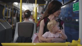 Mother and her little daughter are traveling on public transport in evening, looking out window. Calm pretty mother and daughter sitting by window in bus. A mother kisses her child with great love. - Powered by Shutterstock - Get 15% off with code: PIKWIZARD15